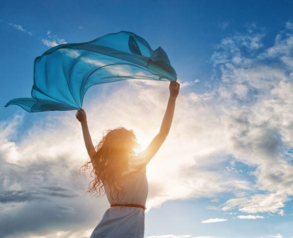 Beautiful young woman on sunset background with blue tissue.